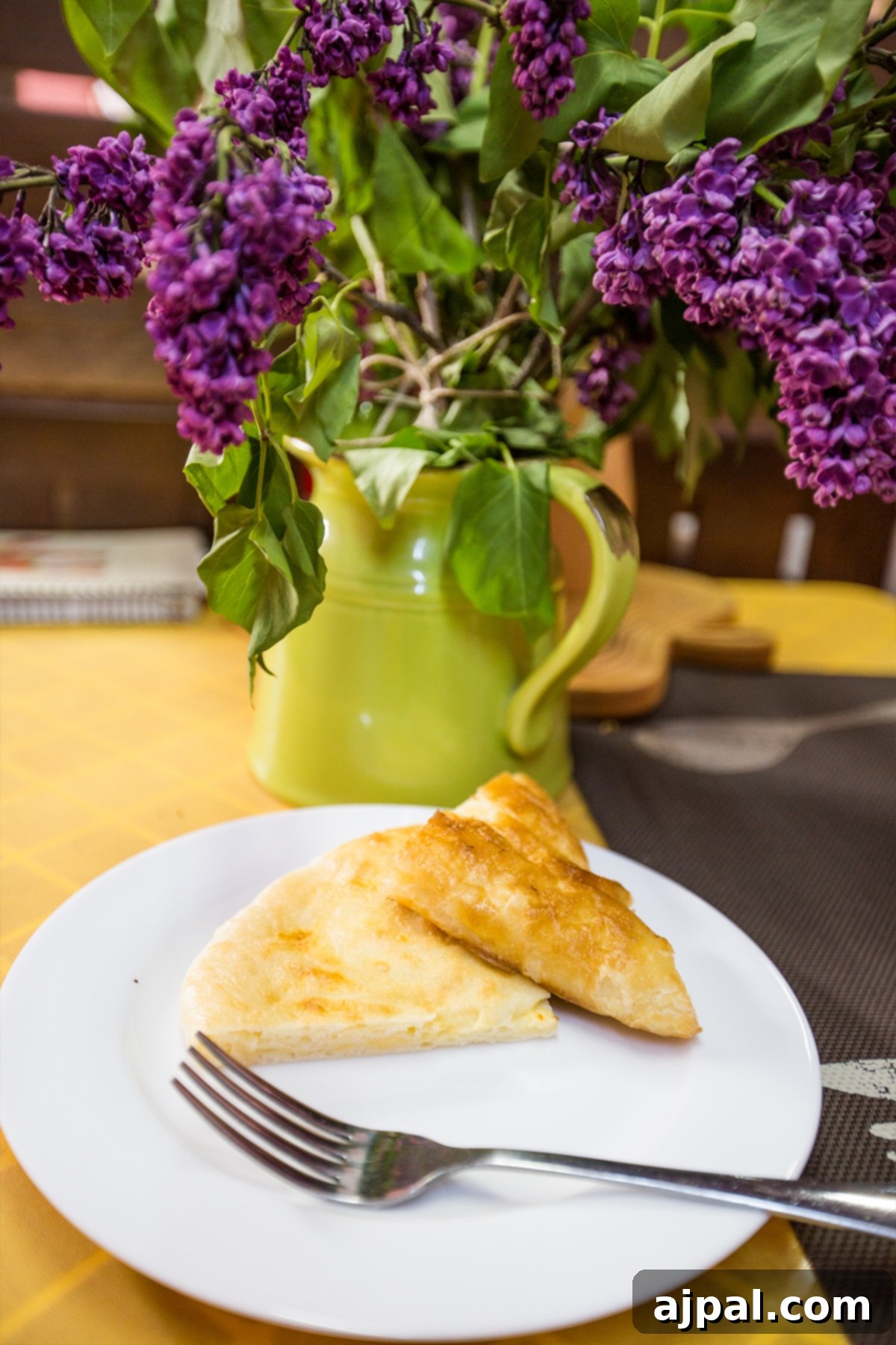 Tbilisi Travel Guide 8 A plate of Khachapuri Adjaruli, with a vibrant setting of lilac flowers in the background.