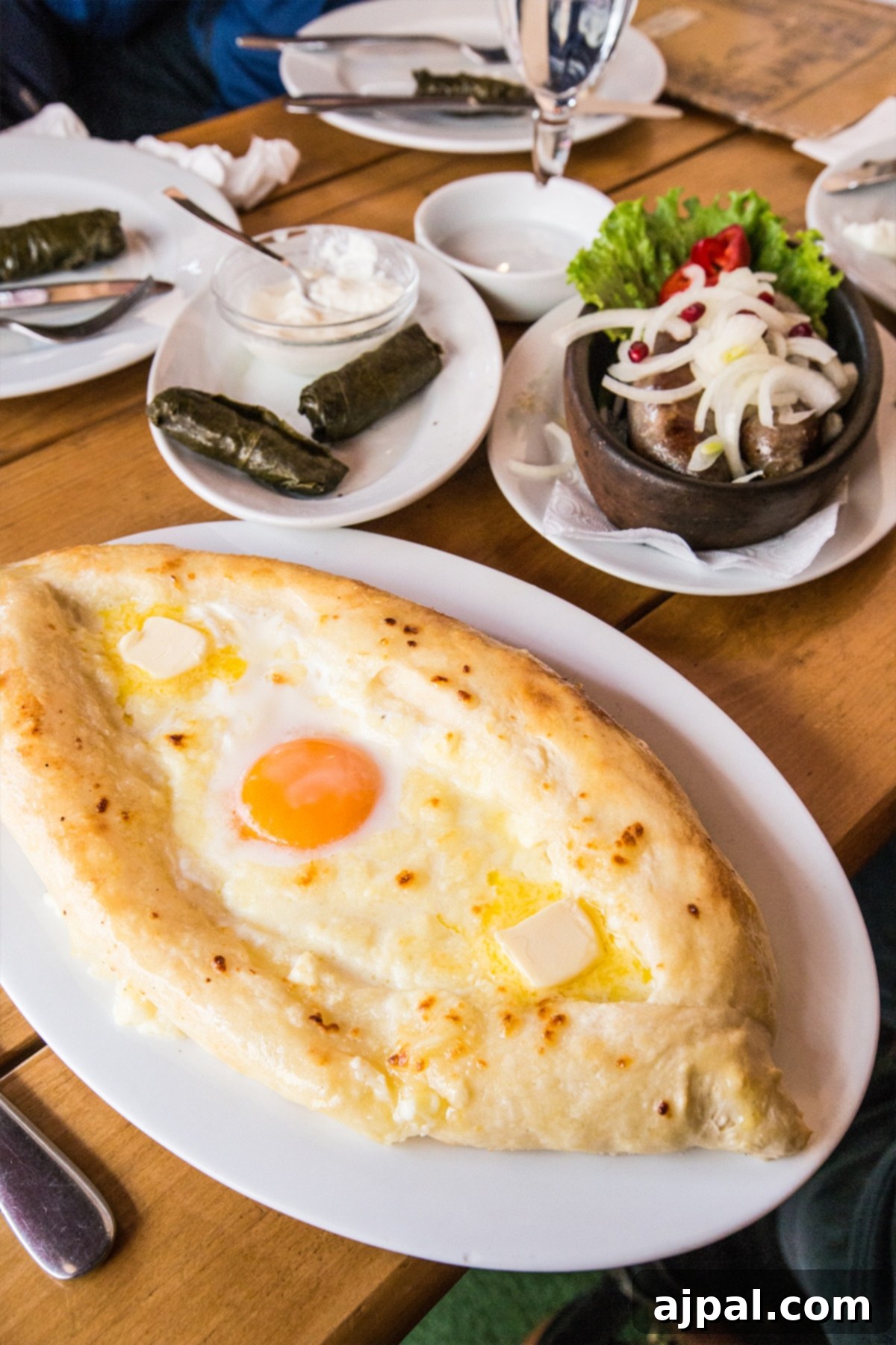 Tbilisi Travel Guide 9 A delectable spread of Khachapuri, sausages, and dolmades at a bustling Tbilisi cafe.