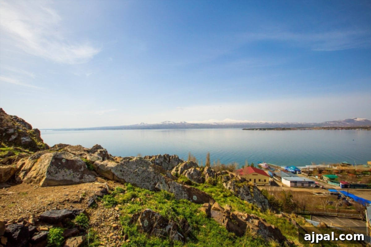 A panoramic view of Lake Sevan and majestic mountains from a rocky cliff near the historic Sevanavank Monastery Ruins in Armenia.