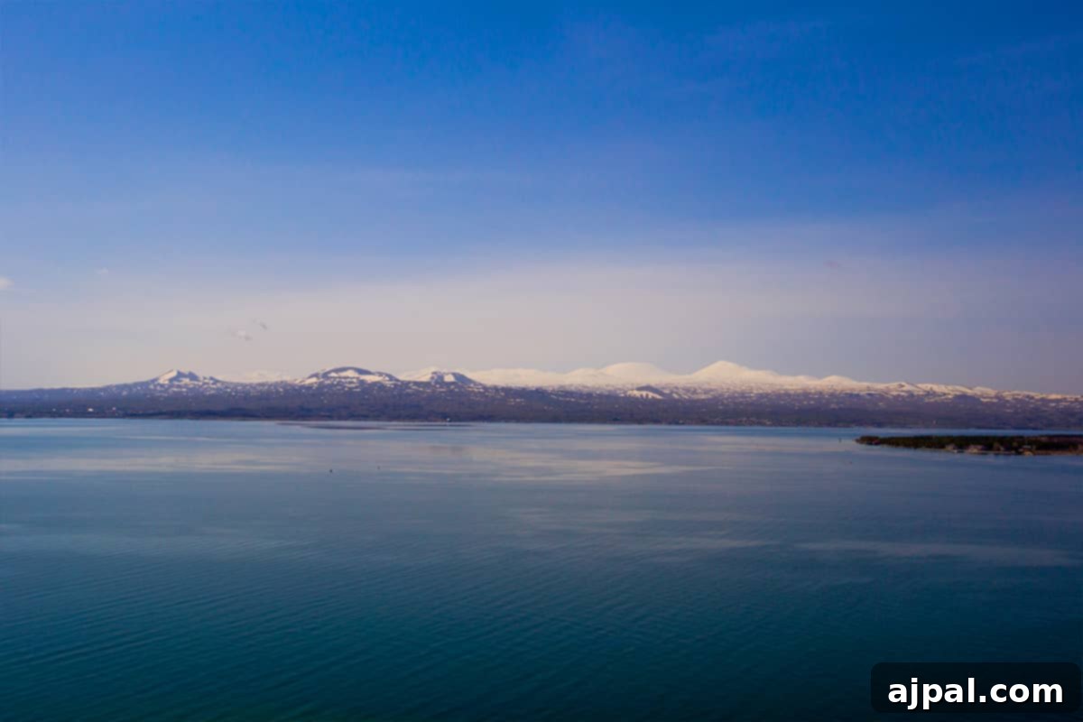 Lake Sevan in Armenia, one of the highest and largest freshwater lakes, framed by snow-capped mountains and featuring the iconic Sevanavank Monastery Ruins.