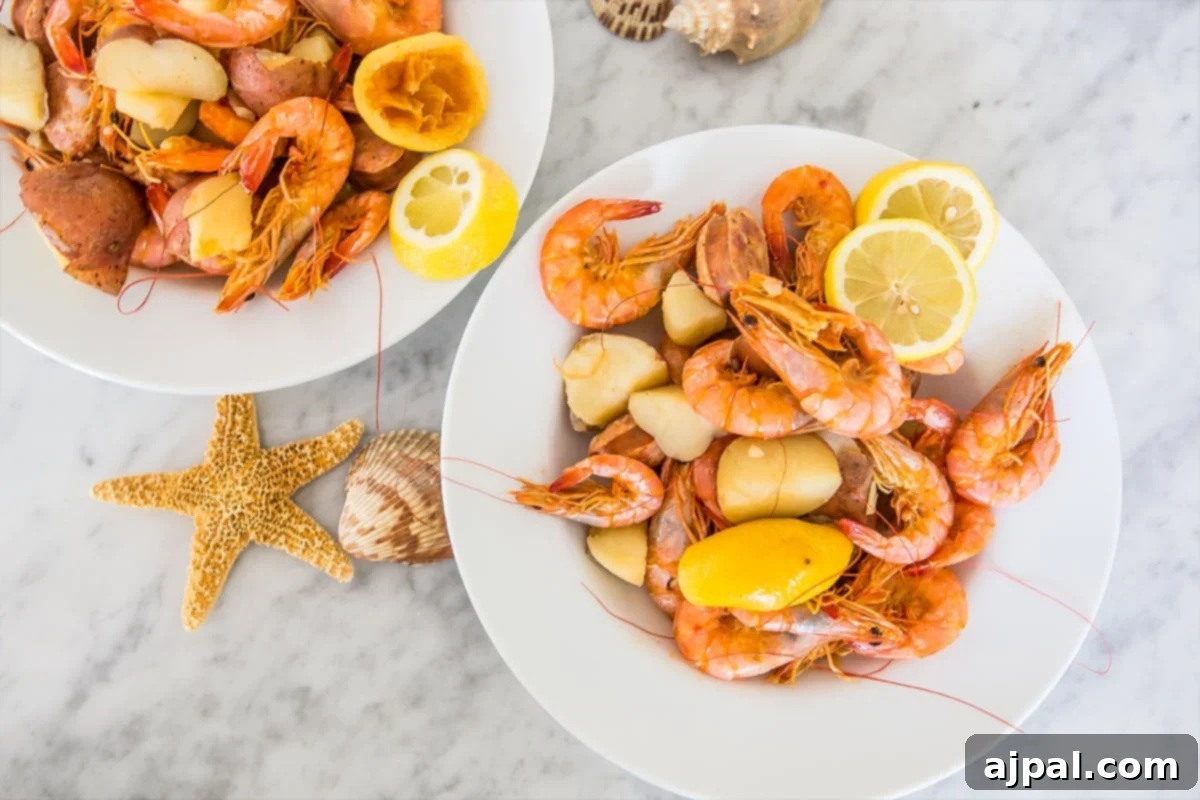 Ultimate Shrimp Boil 5 Three white plates, each generously loaded with a serving of Quick and Easy Shrimp Boil, including shrimp, potatoes, corn, and a lemon wedge, all resting on a elegant marble table.