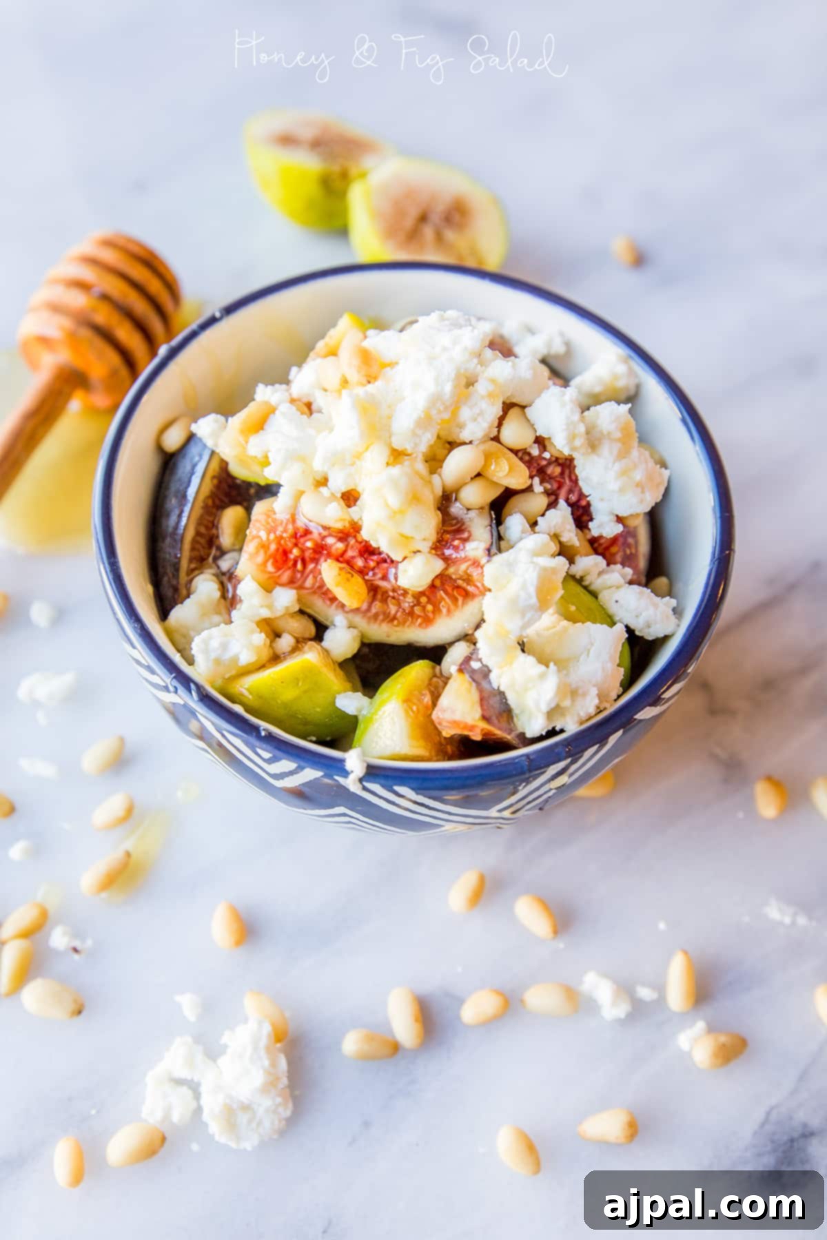 Bowl with fresh figs, crumbled goat cheese, and golden pine nuts, drizzled with honey.
