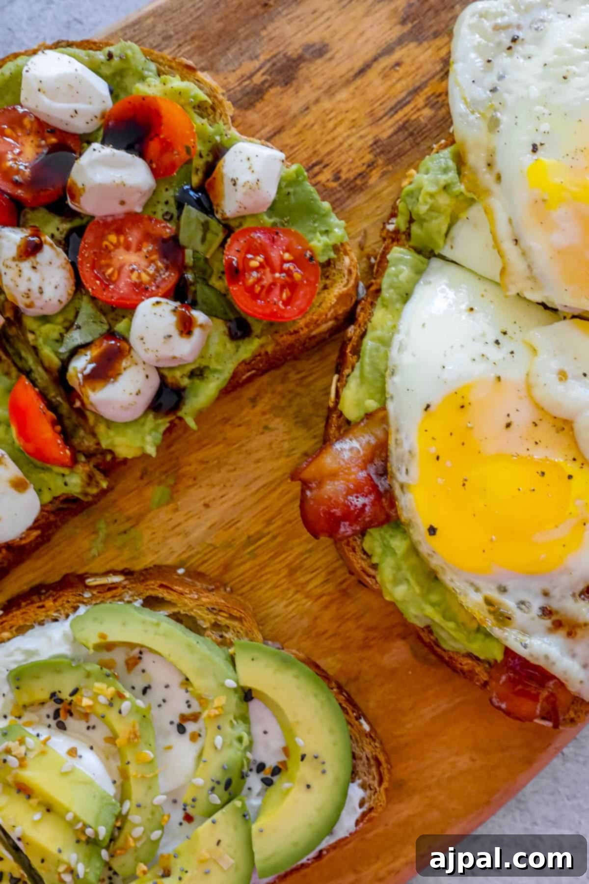 Smashed Avocado Toast 3 Four slices of toast with creamy avocado, crispy bacon, fresh tomatoes, and perfectly fried eggs on a rustic wooden cutting board.