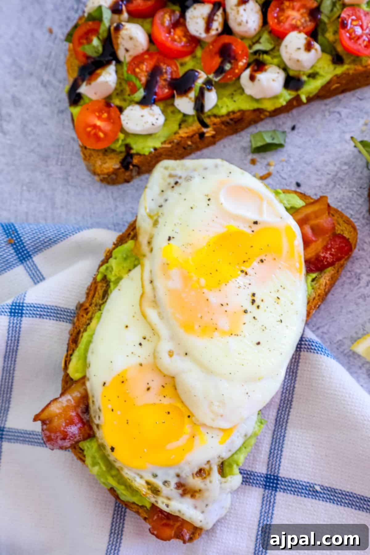 Smashed Avocado Toast 4 A perfectly prepared toast featuring a sunny-side-up egg, brightly colored sliced tomatoes, and creamy avocado spread.