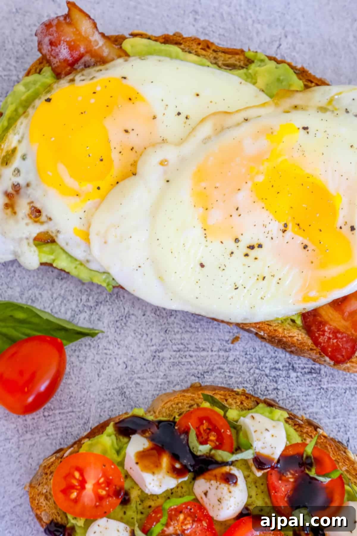 Smashed Avocado Toast 5 Two enticing slices of avocado toast, one topped with an egg and tomatoes, the other with simply avocado, ready for serving.