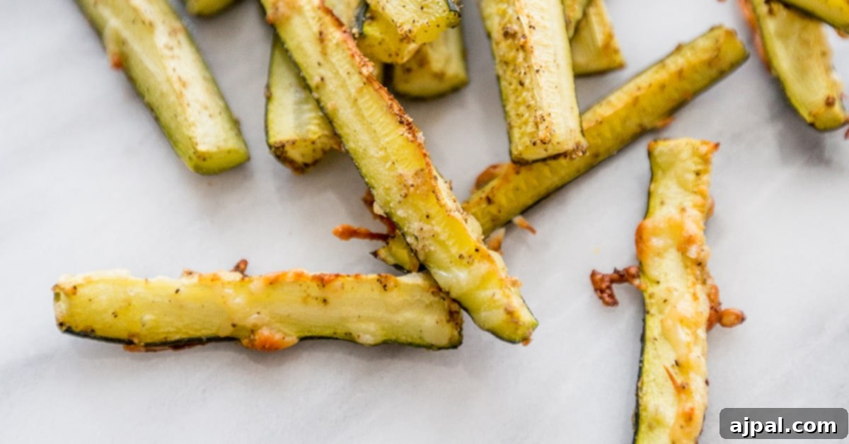 Keto Garlic Parm Zucchini Fries 6 A pile of baked keto Parmesan garlic zucchini fries on a white surface.