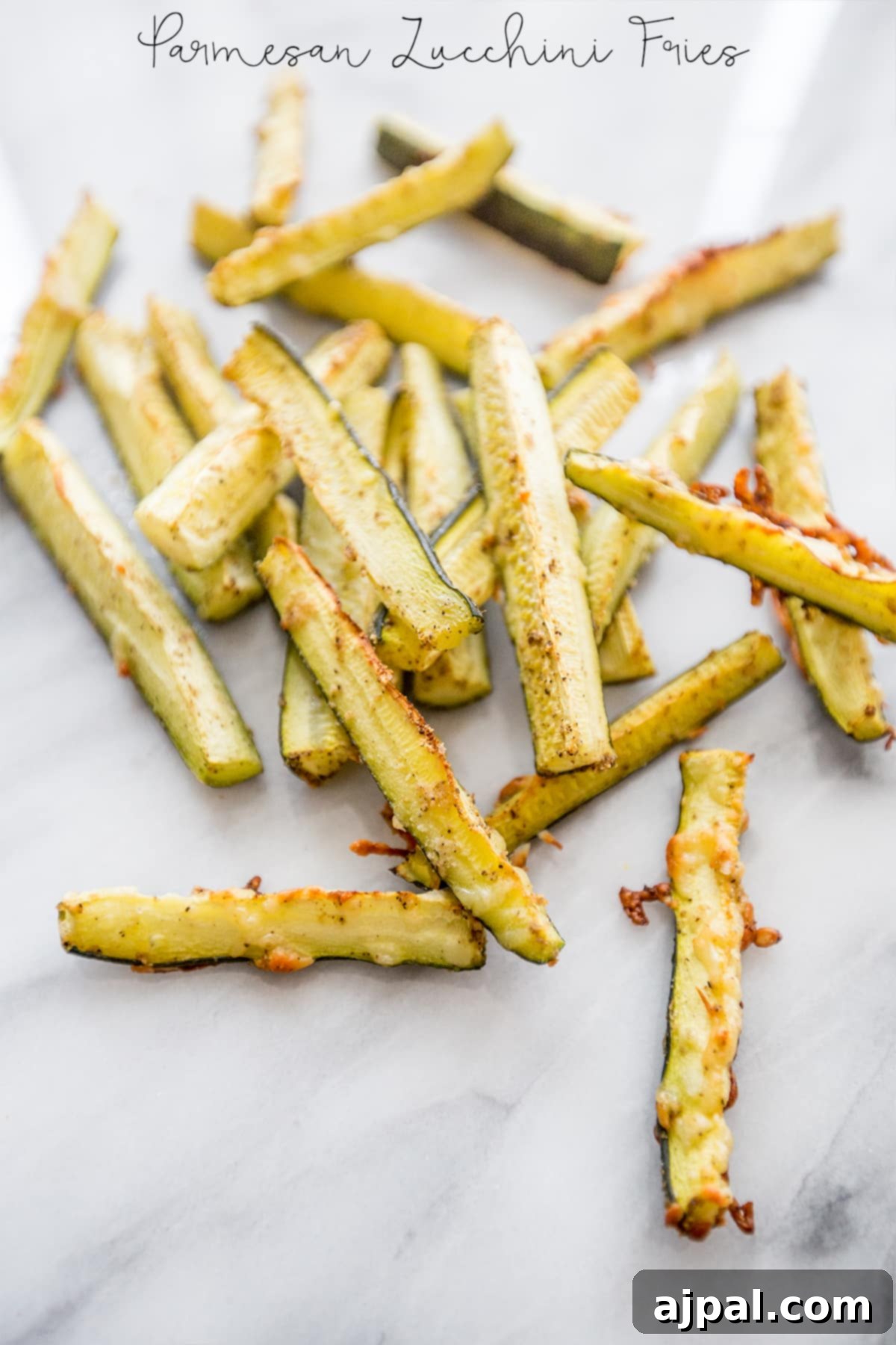 Keto Garlic Parm Zucchini Fries 7 A pile of keto Parmesan garlic zucchini fries on a marble countertop.