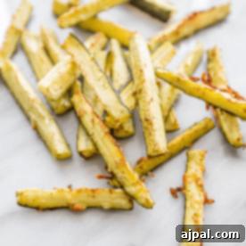 Keto Garlic Parm Zucchini Fries 8 A pile of Parmesan garlic zucchini fries on a marble countertop.