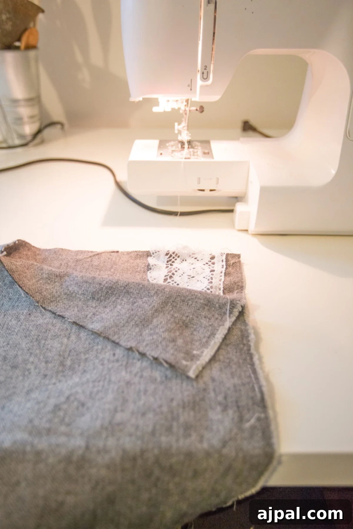 Whip Up a Lace Infinity Scarf in 15 Minutes 6 A sewing machine is actively stitching along the long edge of a folded fabric, creating the main tube of a lace embellished infinity scarf with a precise straight stitch.
