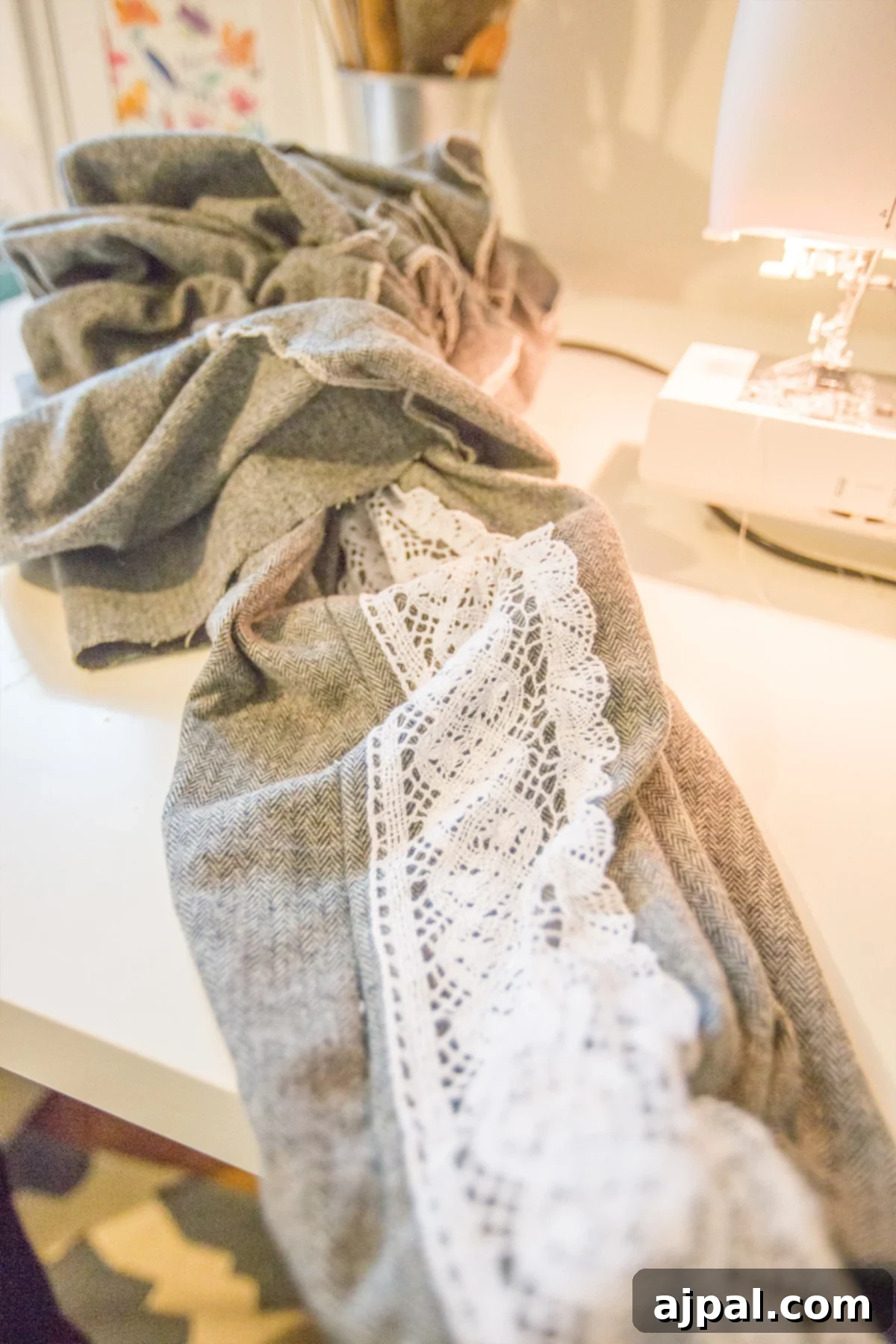 Whip Up a Lace Infinity Scarf in 15 Minutes 7 A length of lace embellished fabric being turned right-side out after sewing, revealing the design and preparing it for the final steps of creating an infinity scarf.