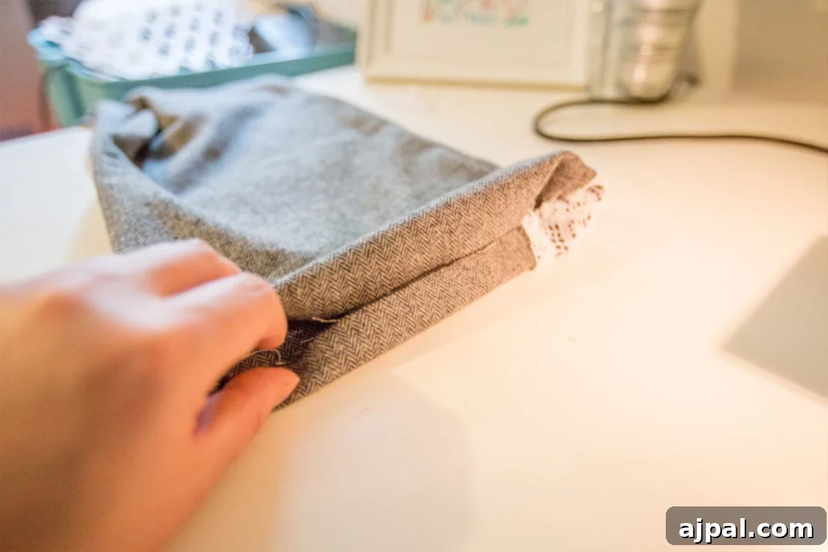 Whip Up a Lace Infinity Scarf in 15 Minutes 8 A person neatly folding in the raw edges of one end of a lace embellished scarf, preparing it for the final step of joining the ends to form an infinity loop.