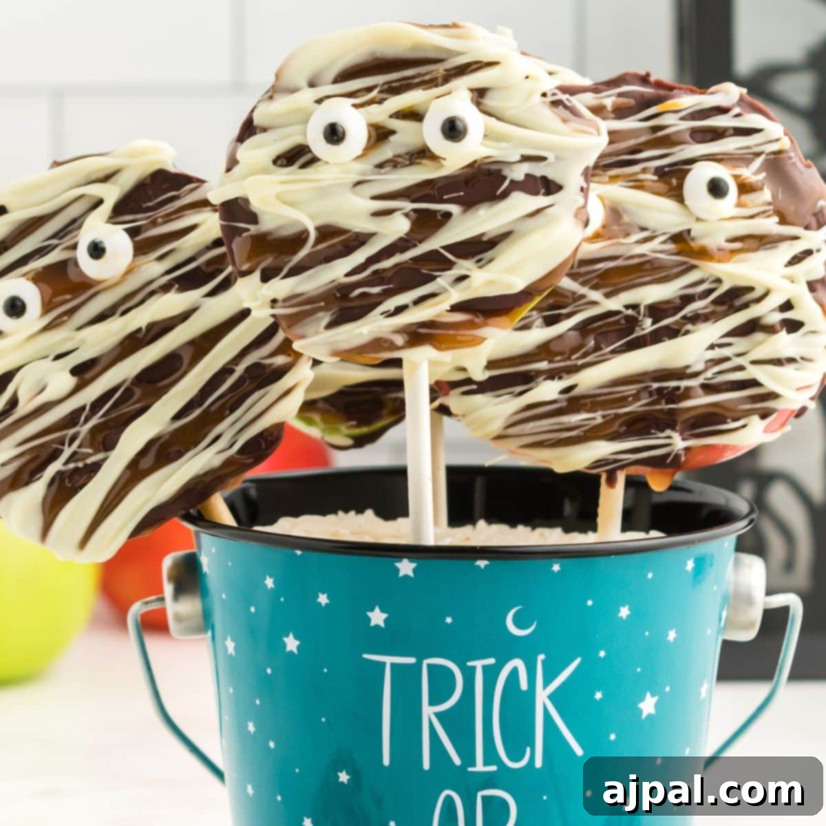 Spooktacular Halloween Treats You Need to Try 17 picture of caramel apples decorated as mummies with chocolate and candy eyes in a blue trick or treat bucket