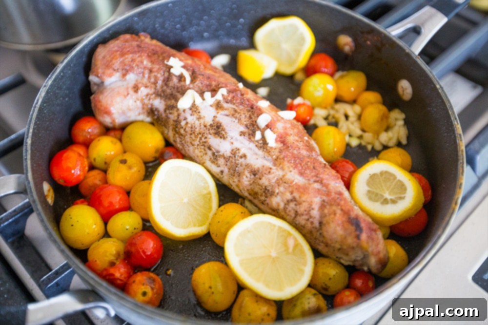 Five-Ingredient Tuscan Pork Loin Skillet Dinner 3 Picture of pork tenderloin browning in a pan with lemon and tomatoes, creating a beautiful color.