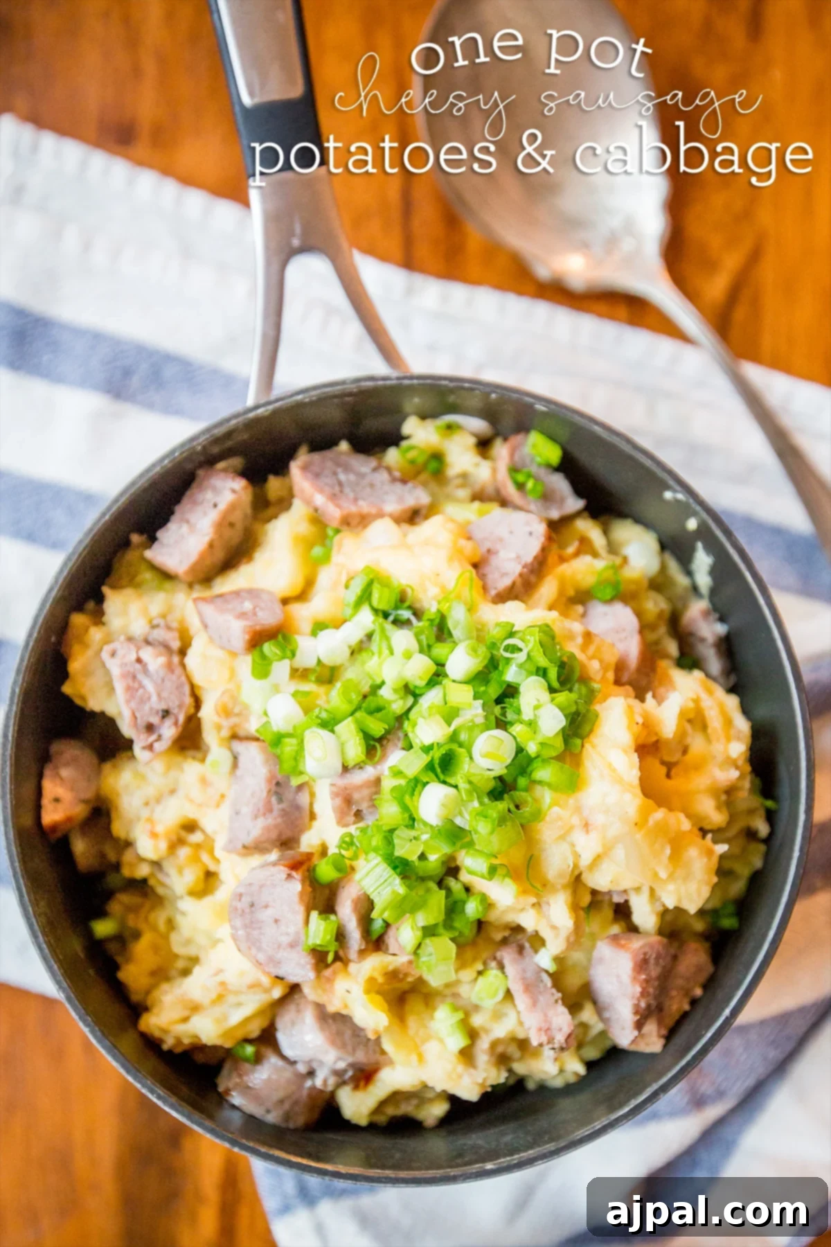 Hearty Cheesy Sausage Potato and Cabbage Bake 3 Close-up of a cheesy potato and cabbage skillet dinner, topped with fresh green onions