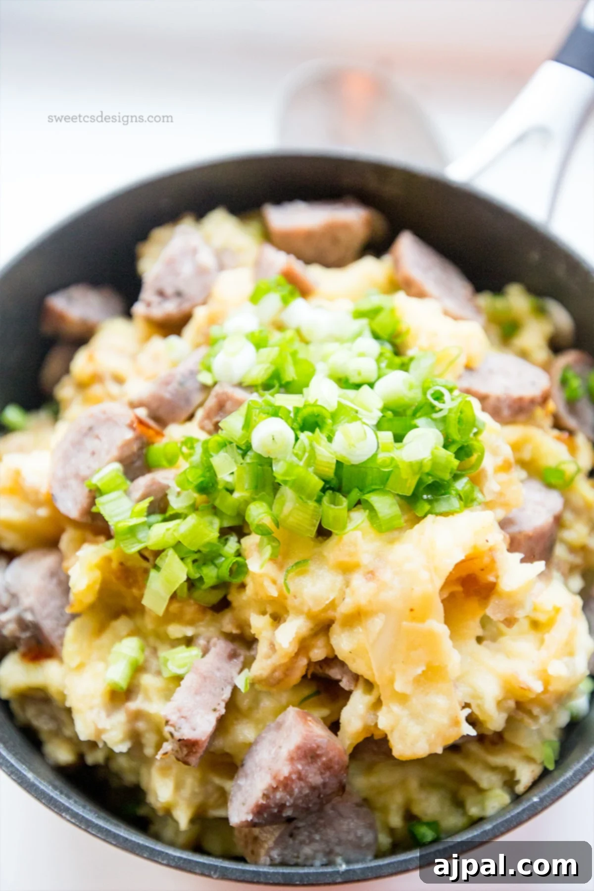 Hearty Cheesy Sausage Potato and Cabbage Bake 4 A savory skillet of cheesy sausage and potatoes, garnished with vibrant green onions