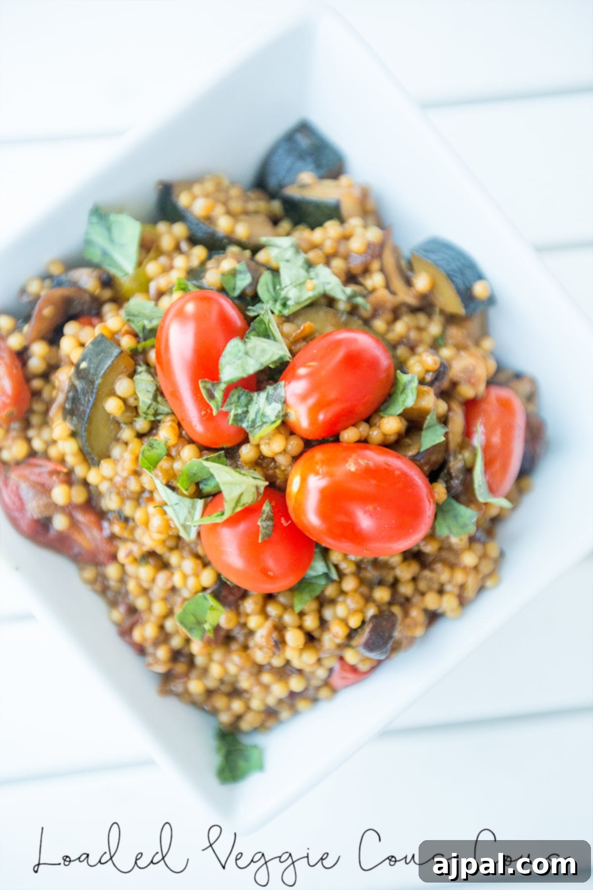 A colorful bowl of couscous with sautéed onions, mushrooms, zucchini, tomatoes, and fresh basil, ready to be served.