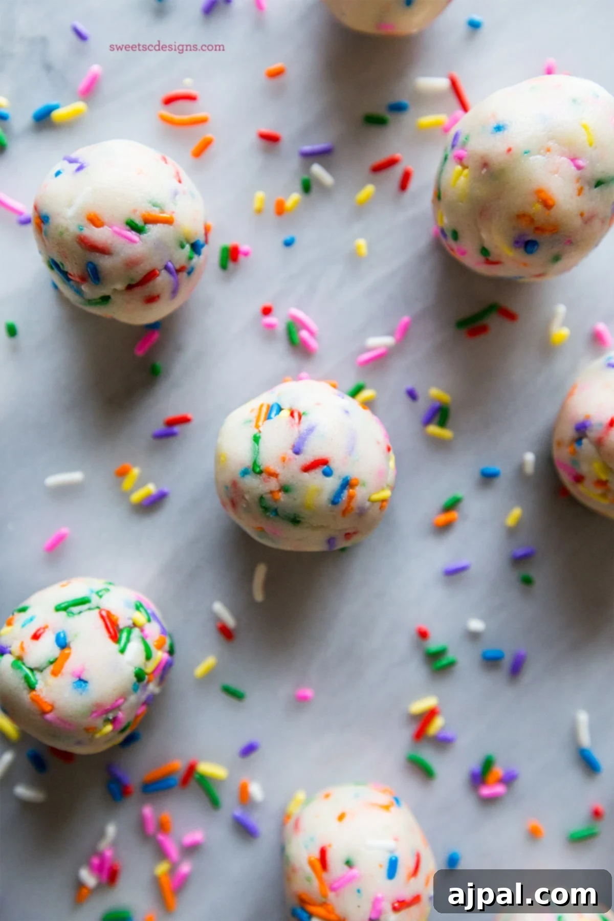 Easy 2 Ingredient Cake Batter Truffles 2 Vibrant rainbow sprinkles coating delightful no-bake cake batter truffles, arranged on a smooth marble surface, ready to be enjoyed.