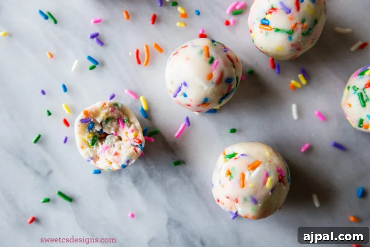 Easy 2 Ingredient Cake Batter Truffles 3 Close-up of fluffy no-bake cake batter truffles adorned with colorful sprinkles, sitting on a pristine marble counter, highlighting their deliciousness.