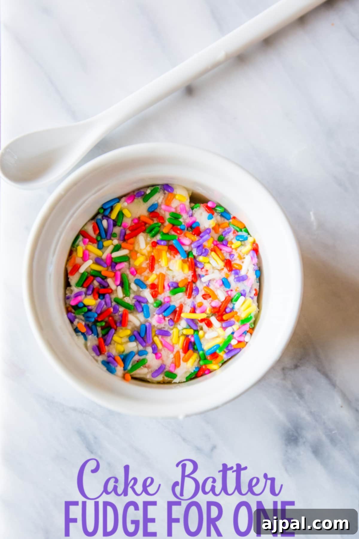 A close-up of a single serving of cake batter fudge in a white bowl, adorned with colorful sprinkles, ready to be enjoyed.