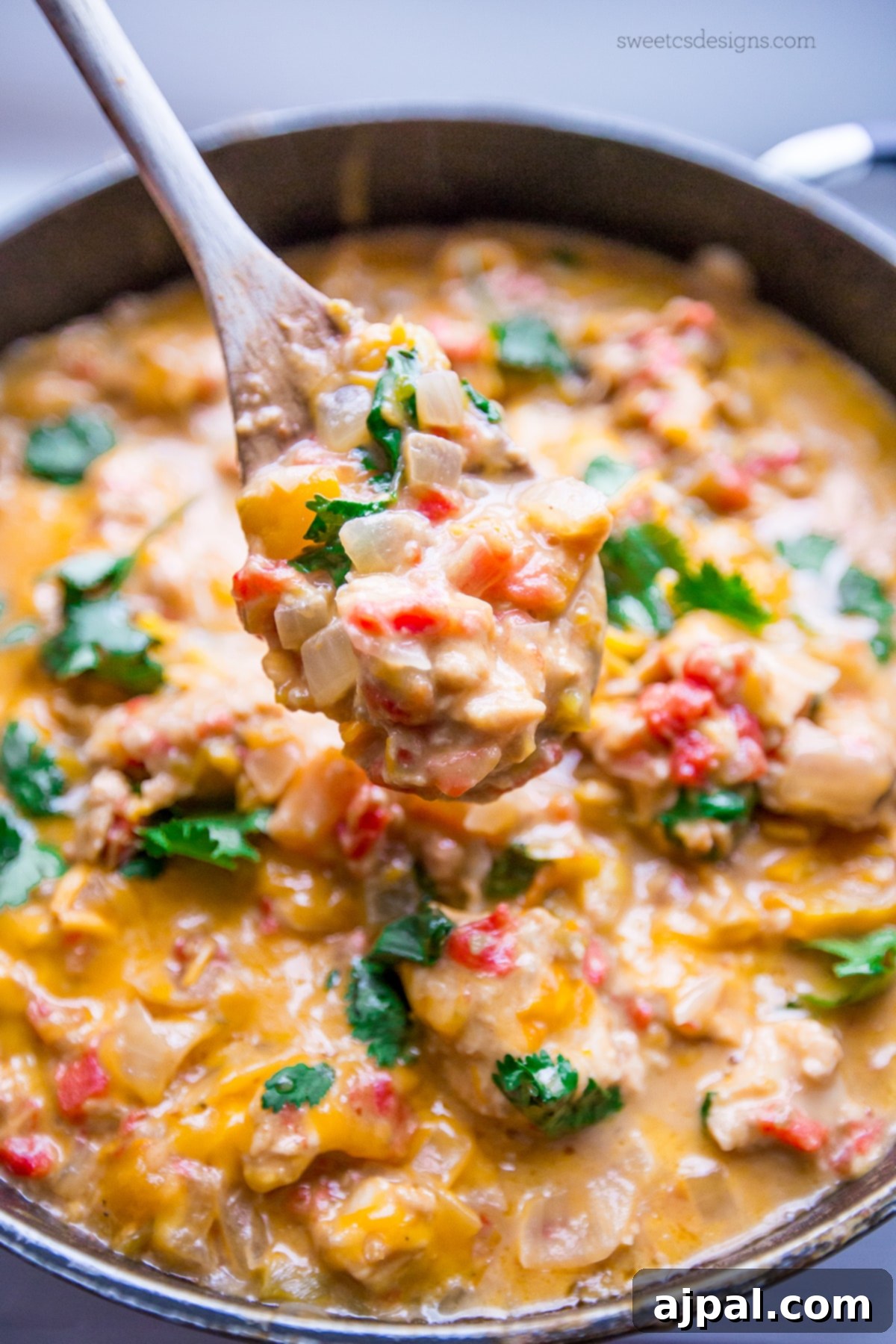 A close-up shot of a creamy, spicy One Pot Cheesy Chicken and Green Chile Skillet, featuring tender chicken, melted cheese, and vibrant green chiles, ready to be served over rice or in a burrito bowl.