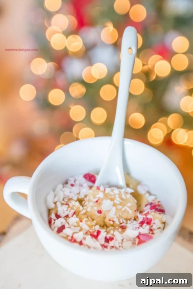 A festive white bowl with a spoon in front of a Christmas tree adorned with peppermint cookies.