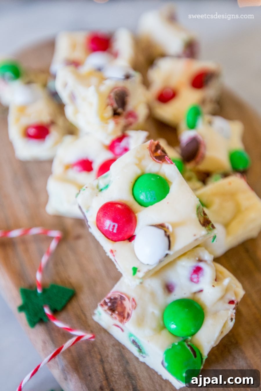 Festive Confectionery Fudge 3 Close-up of cookie dough fudge adorned with an assortment of colorful Christmas candies, set on a wooden surface, highlighting its vibrant appearance.