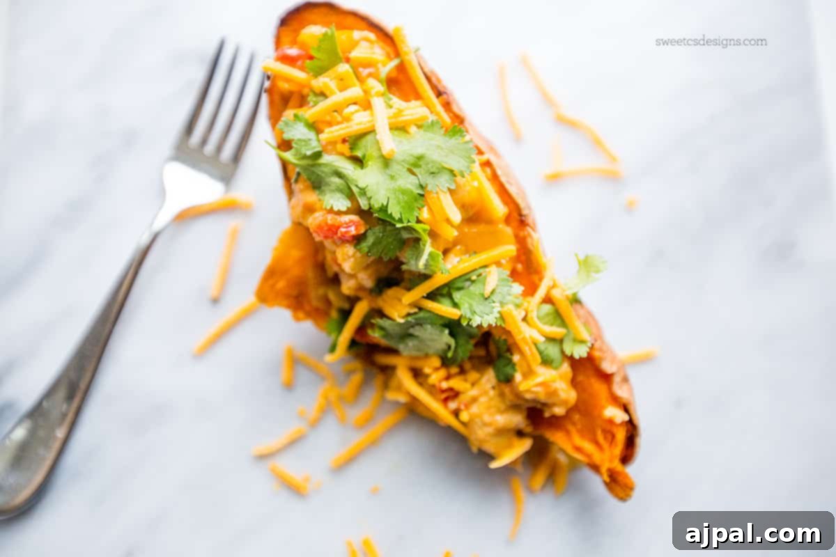 Southwestern Chicken Stuffed Sweet Potatoes 3 Close-up of a perfectly cooked sweet potato filled with green chile chicken, topped with melted cheese and a sprinkle of cilantro.