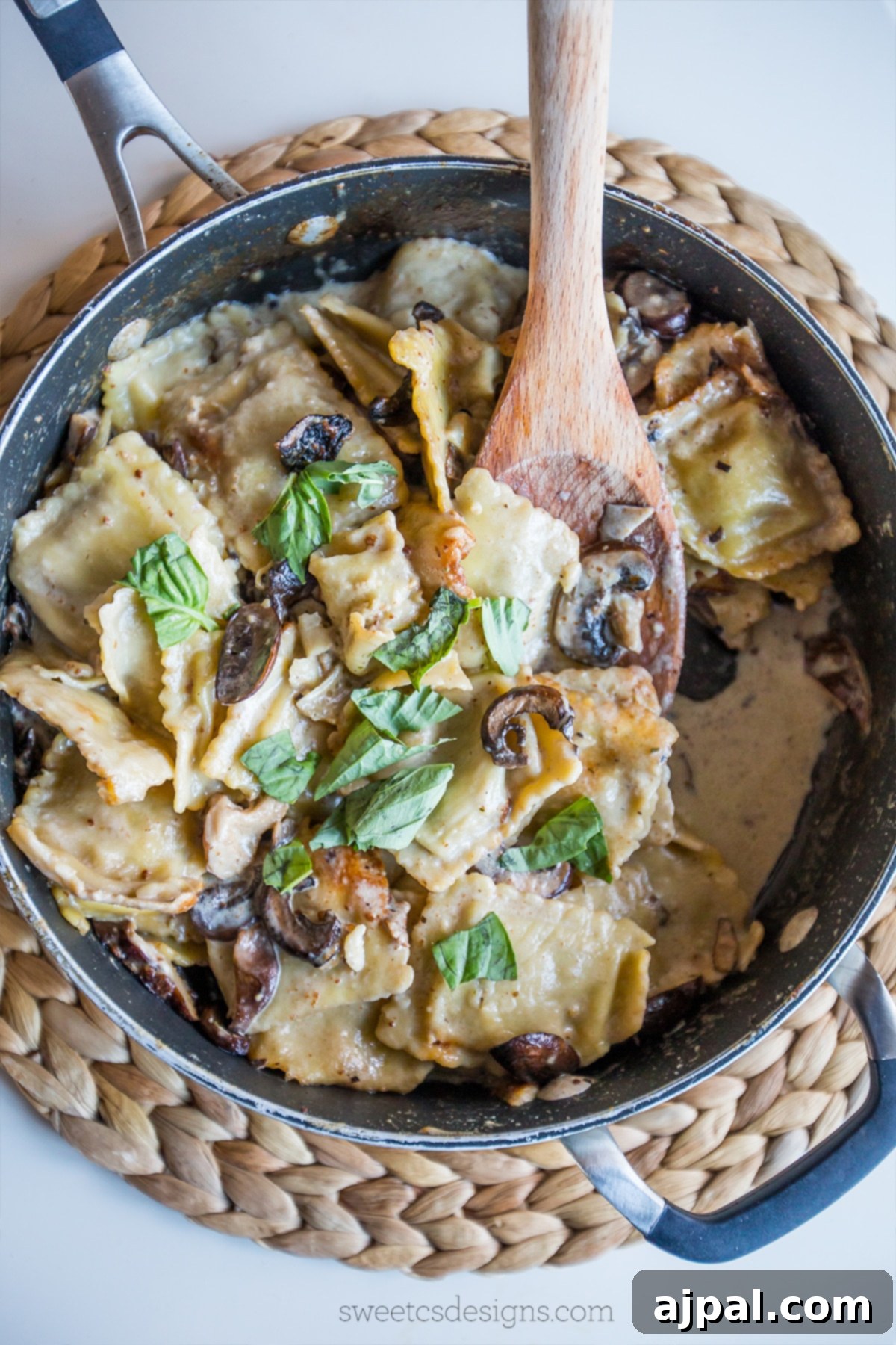 Preparing Skillet Ravioli Stroganoff, stirring beef ravioli, mushrooms, and basil in a creamy sauce with a wooden spoon.