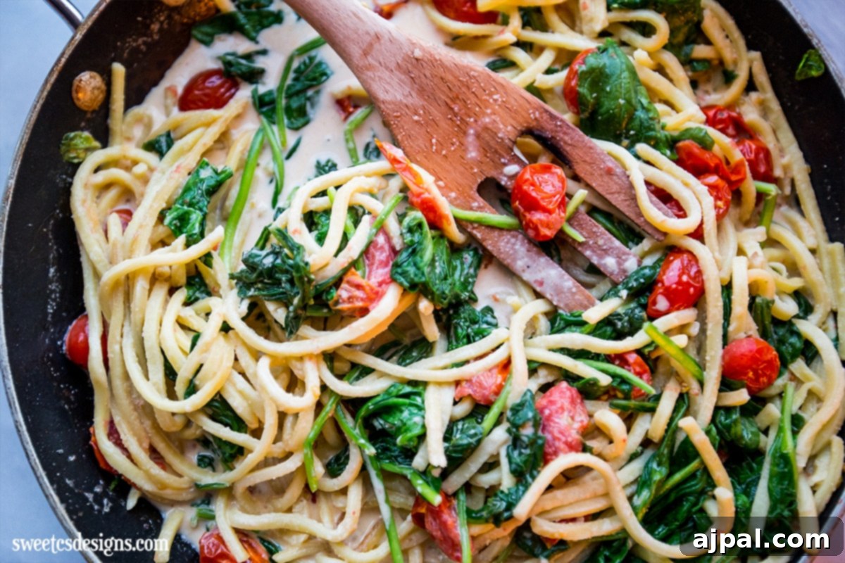 Rich and delicious creamy one-pot Alfredo pasta skillet with spinach and a wooden spoon.