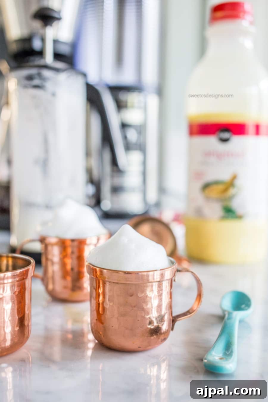 Holiday Eggnog Espresso Kick 3 Copper small mug with milk foam on it, eggnog in the background, highlighting the festive setup