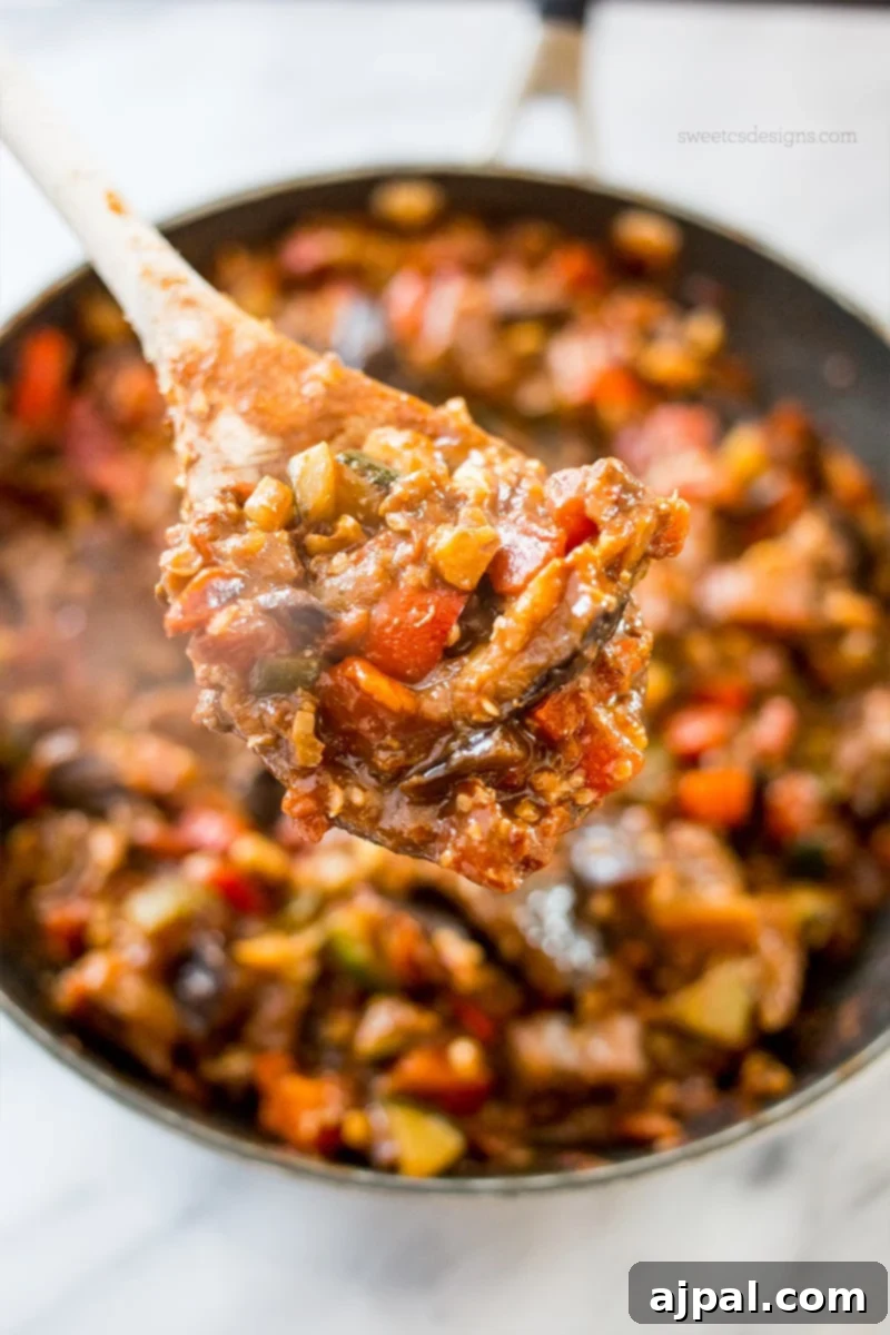 Hearty Paleo Vegan Taco Skillet 3 A wooden spoon lifting a scoop of delicious vegan taco skillet from a hot pan, showcasing the rich, savory filling.