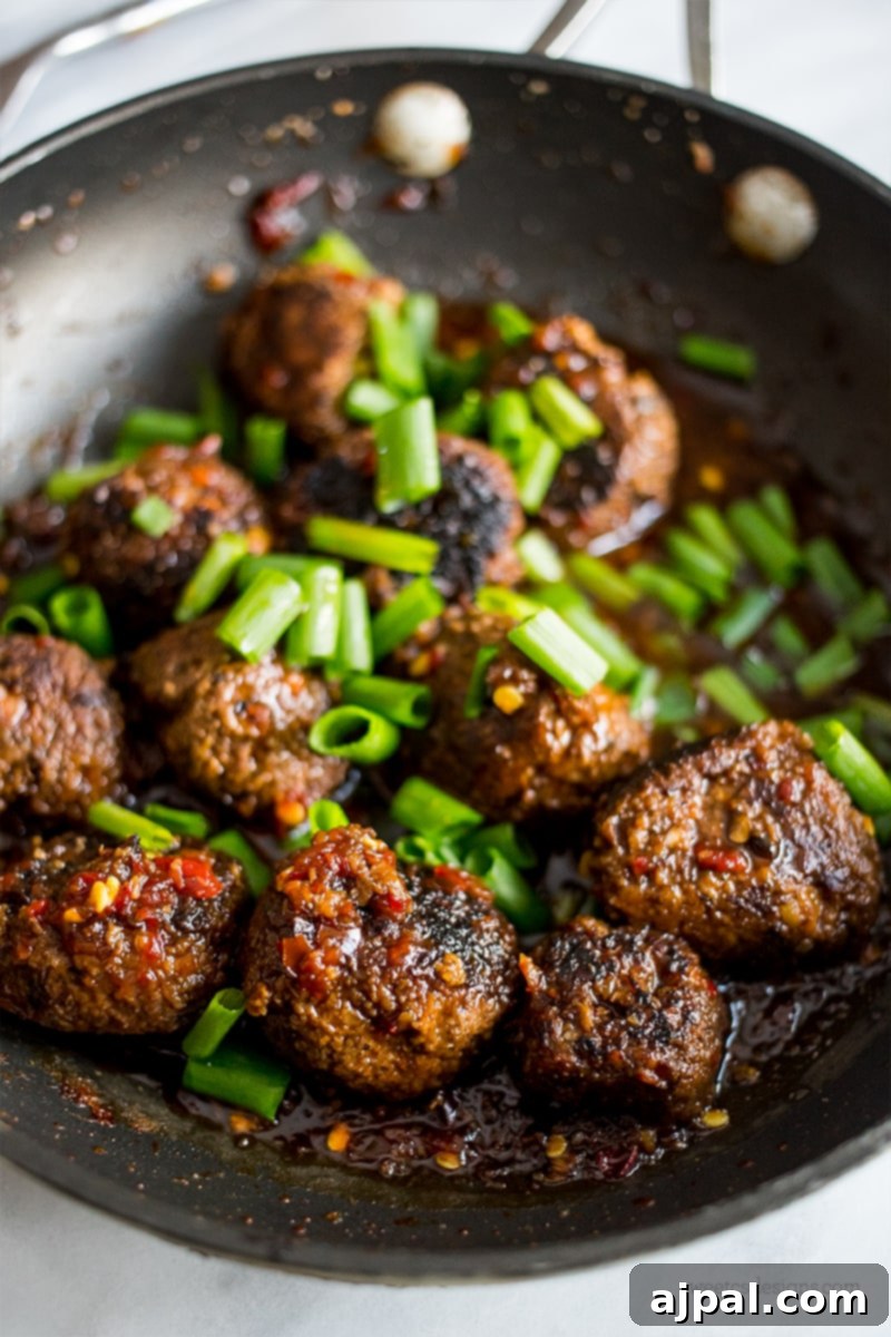 Sticky Vegan Hoisin Meatballs 3 Vegan Hoisin Meatballs being cooked in a wok with rich hoisin sauce and fresh green onions.