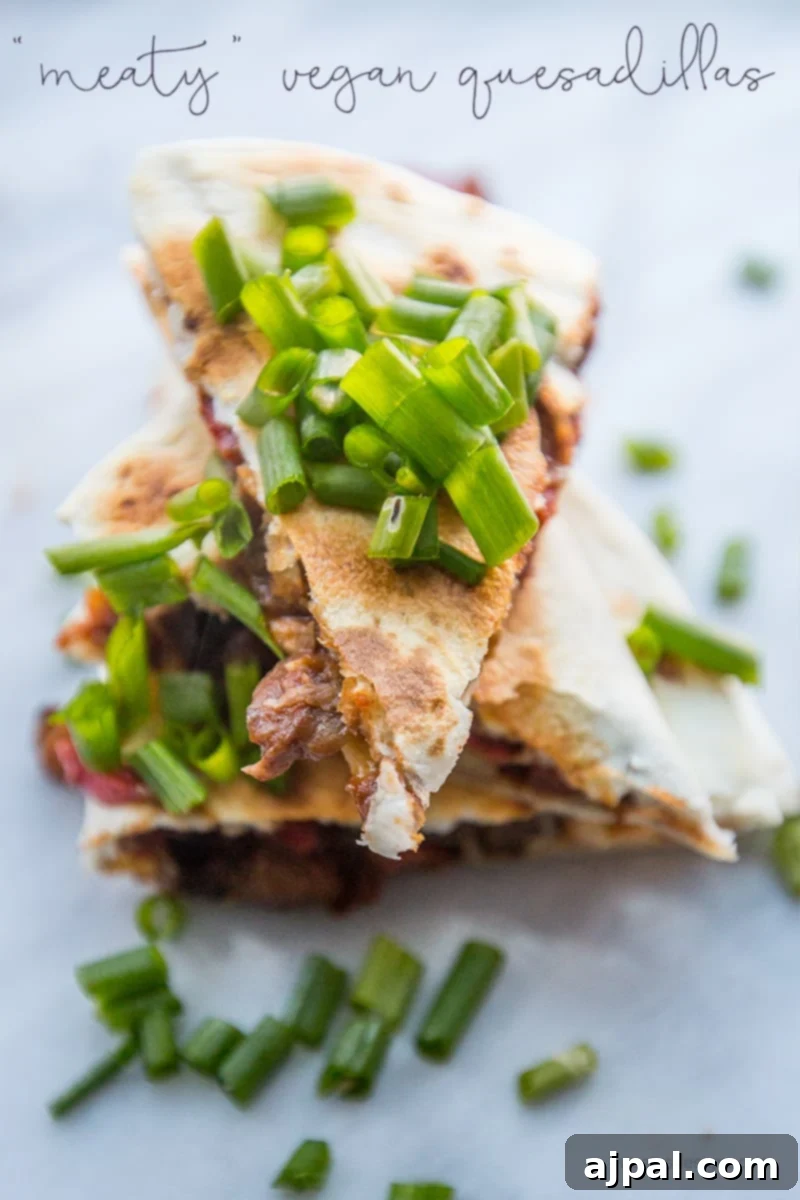 Stacked meaty vegan quesadillas topped with fresh green onions, showcasing a delicious plant-based meal ready to be enjoyed.