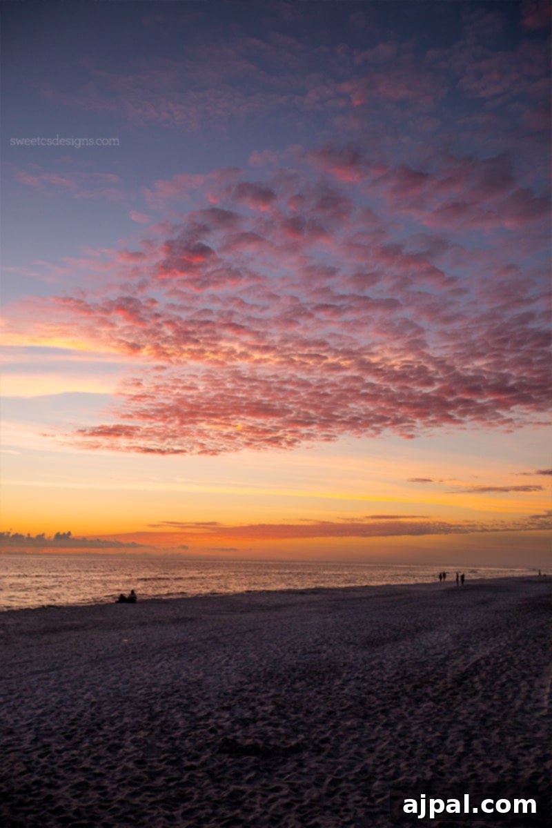 Yuletide in Paradise Seaside Florida 13 People enjoying a vibrant Christmas sunset stroll on the sandy beach of Seaside, Florida, against a picturesque sky.