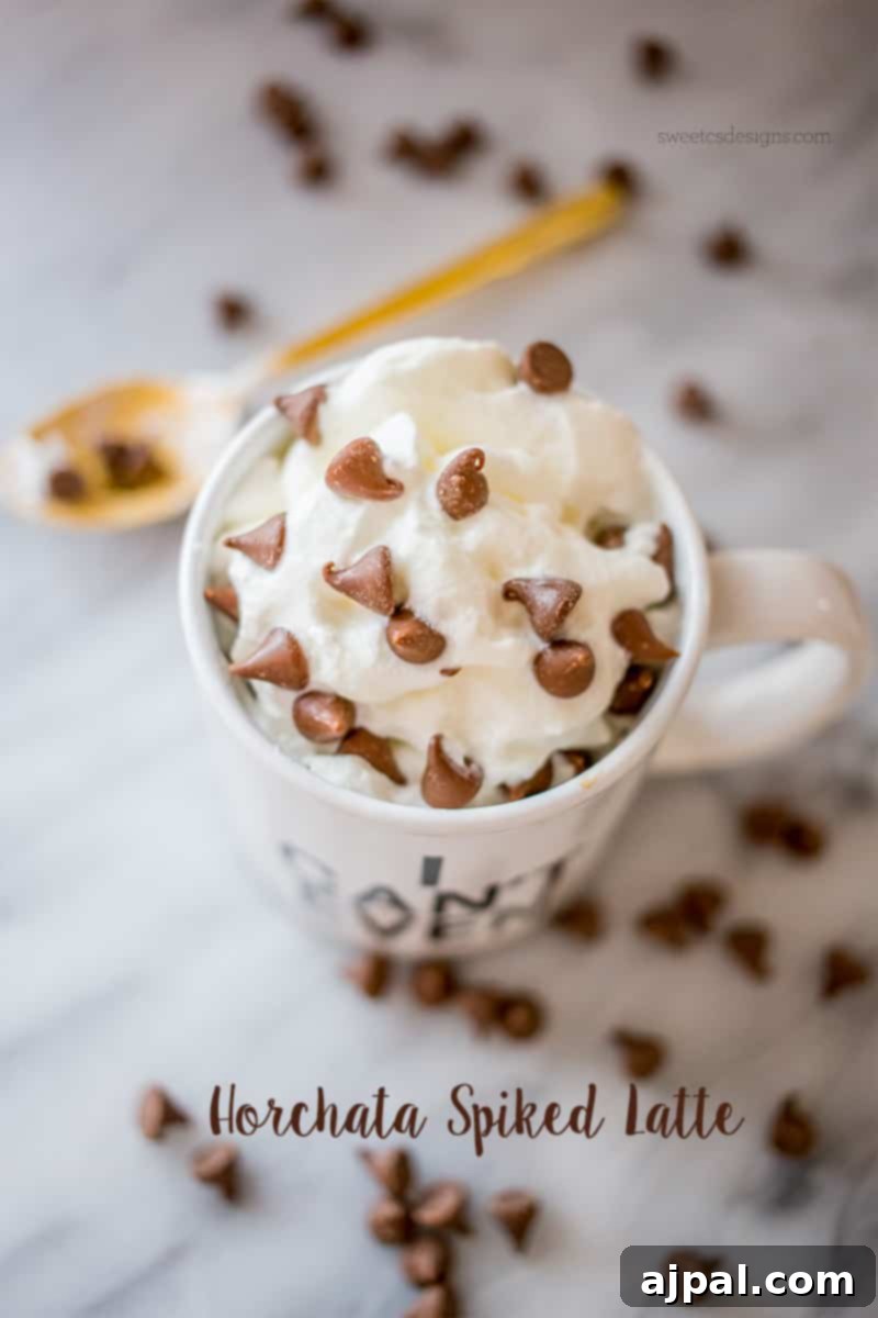 Spirited Horchata Delight 3 Overhead view of an 'I Can't Even' mug filled with a Horchata Spiked Latte, adorned with whipped cream and chocolate chips, and a golden spoon.