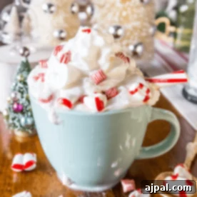 White Peppermint Mocha 6 A light blue mug filled with whipped cream, topped with red and white peppermint candies and a candy cane stick, on a wooden surface with festive holiday decorations, representing a cozy white cocoa peppermint latte.