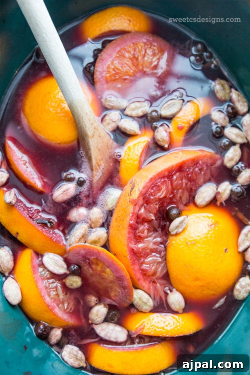 Spiced Winter Warmer 4 Close-up shot of a slow cooker filled with traditional Glühwein, featuring vibrant sliced oranges, dark peppercorns, and green cardamom pods simmering gently, promising a comforting holiday drink.