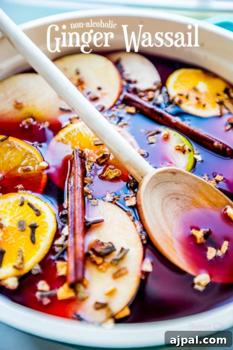 Pink drink with orange slices, apple slices, cloves, and cinnamon sticks, with a wooden spoon for serving.