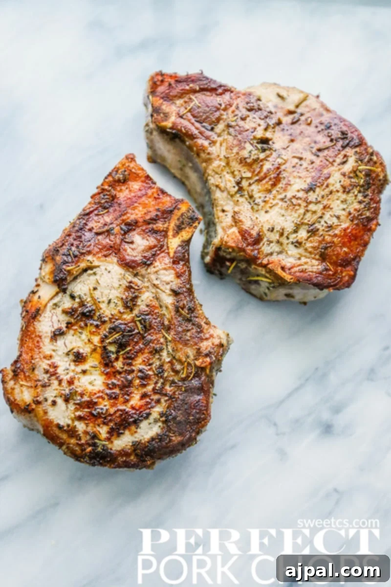 Perfectly cooked Herbs de Provence pork chops garnished with fresh herbs on a marble countertop, promising a delicious and juicy meal.