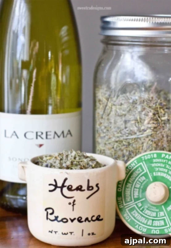 A jar of homemade Herbs de Provence seasoning blend, ready to infuse dishes with Mediterranean flavors, next to a bottle of olive oil.