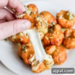 A person enjoying fried cheese bombs by dipping a fork into a plate of crispy delights.