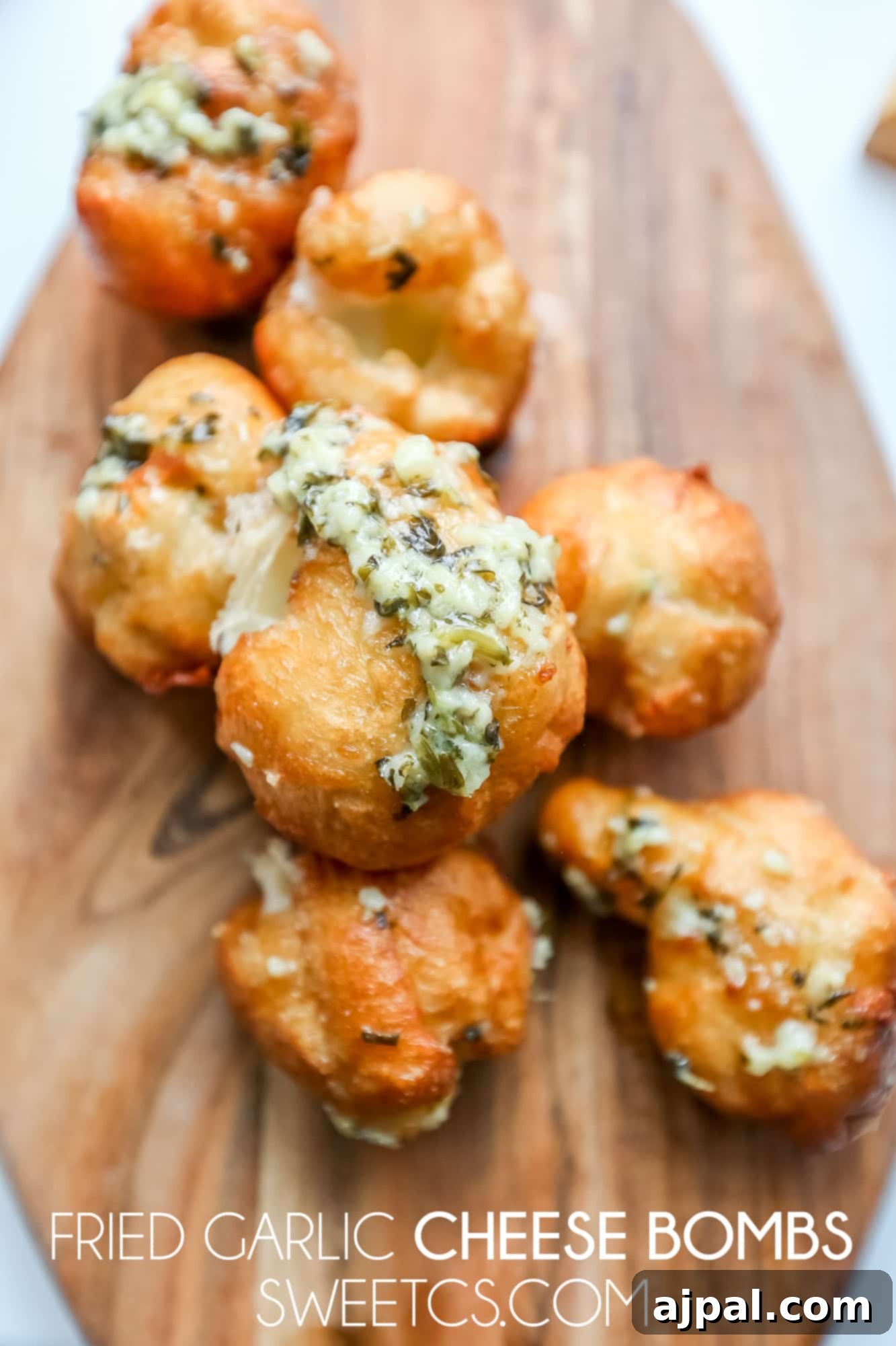 Crispy Garlic Cheese Blasts 7 A cutting board holds freshly fried garlic cheese bombs, some cut open to reveal the melted cheese.