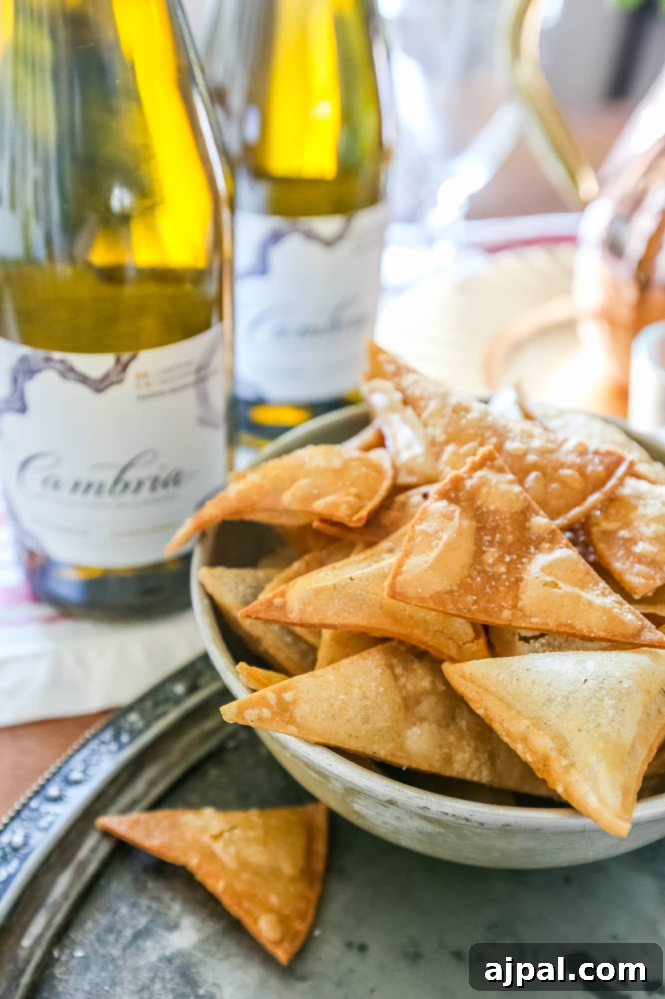 Crispy Homemade Tortilla Chips with Zesty Green Chile Cheese Dip 3 A close-up view of golden, perfectly seasoned homemade tortilla chips, ready for dipping, with a elegant glass of Cambria wine subtly blurred in the background, creating a sophisticated ambiance.