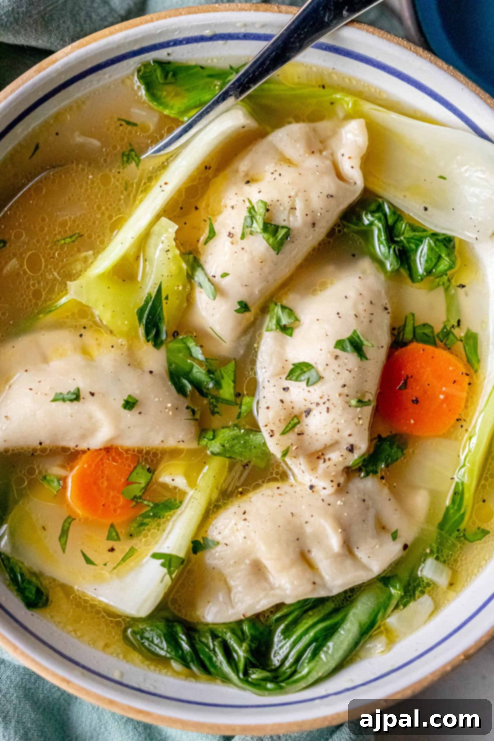 Easy 15-Minute One-Pot Potsticker Soup 14 A 15-minute potsticker soup featuring a bowl of savory broth with dumplings, bok choy, and carrot slices, garnished with chopped herbs.