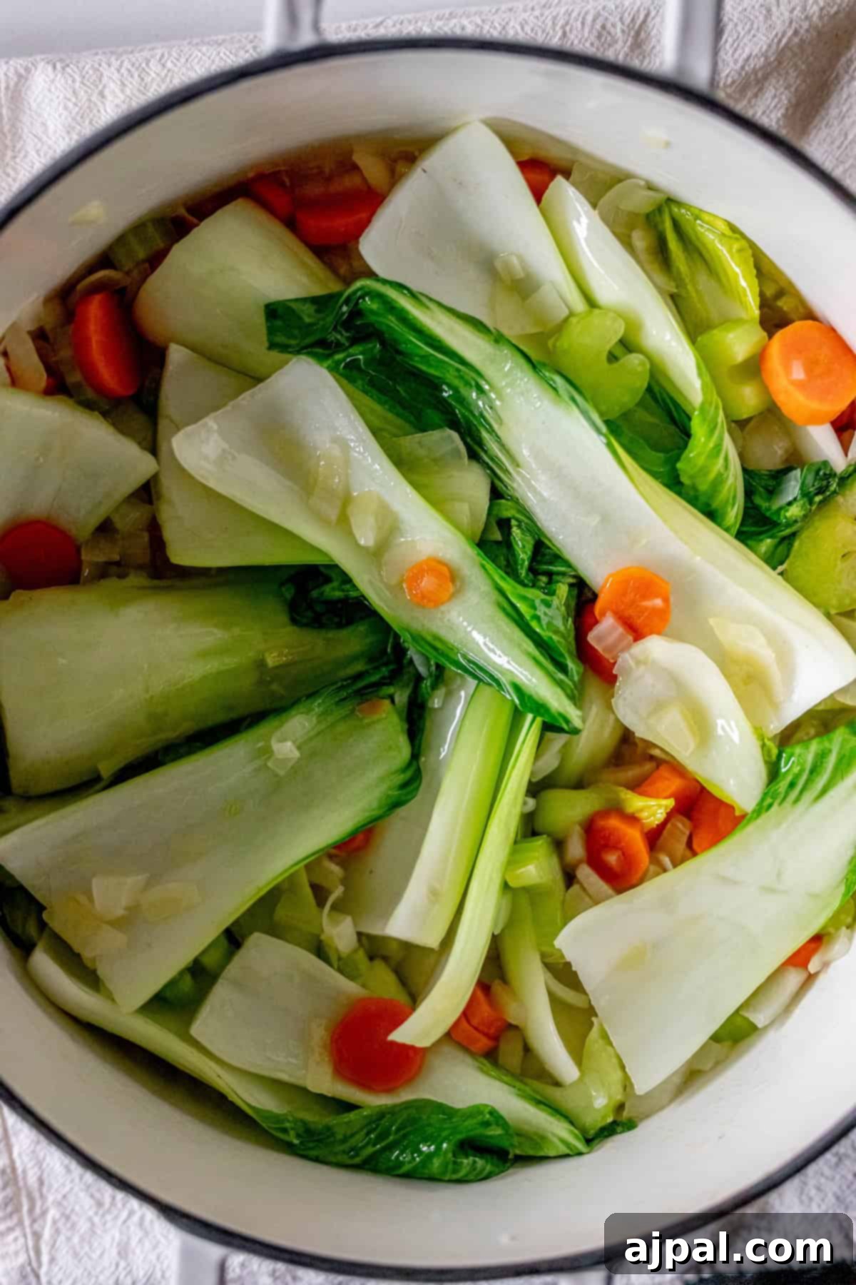 Easy 15-Minute One-Pot Potsticker Soup 9 A pot filled with chopped bok choy, carrots, and other vibrant vegetables awaits on a light-colored surface, promising a delightful 15 minute potsticker soup.