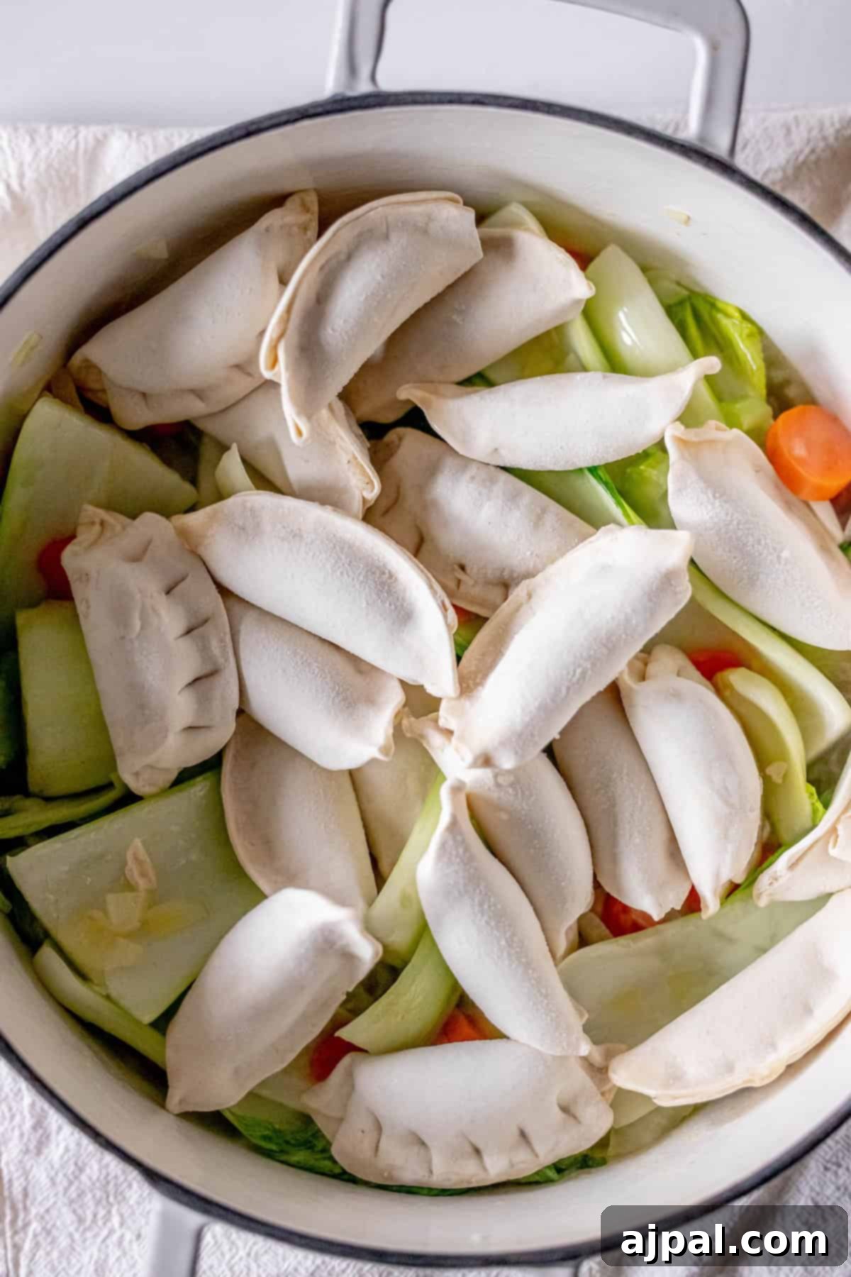 Easy 15-Minute One-Pot Potsticker Soup 10 A pot is filled with frozen dumplings atop a colorful mix of bok choy and carrots, creating the perfect base for a 15-minute potsticker soup.
