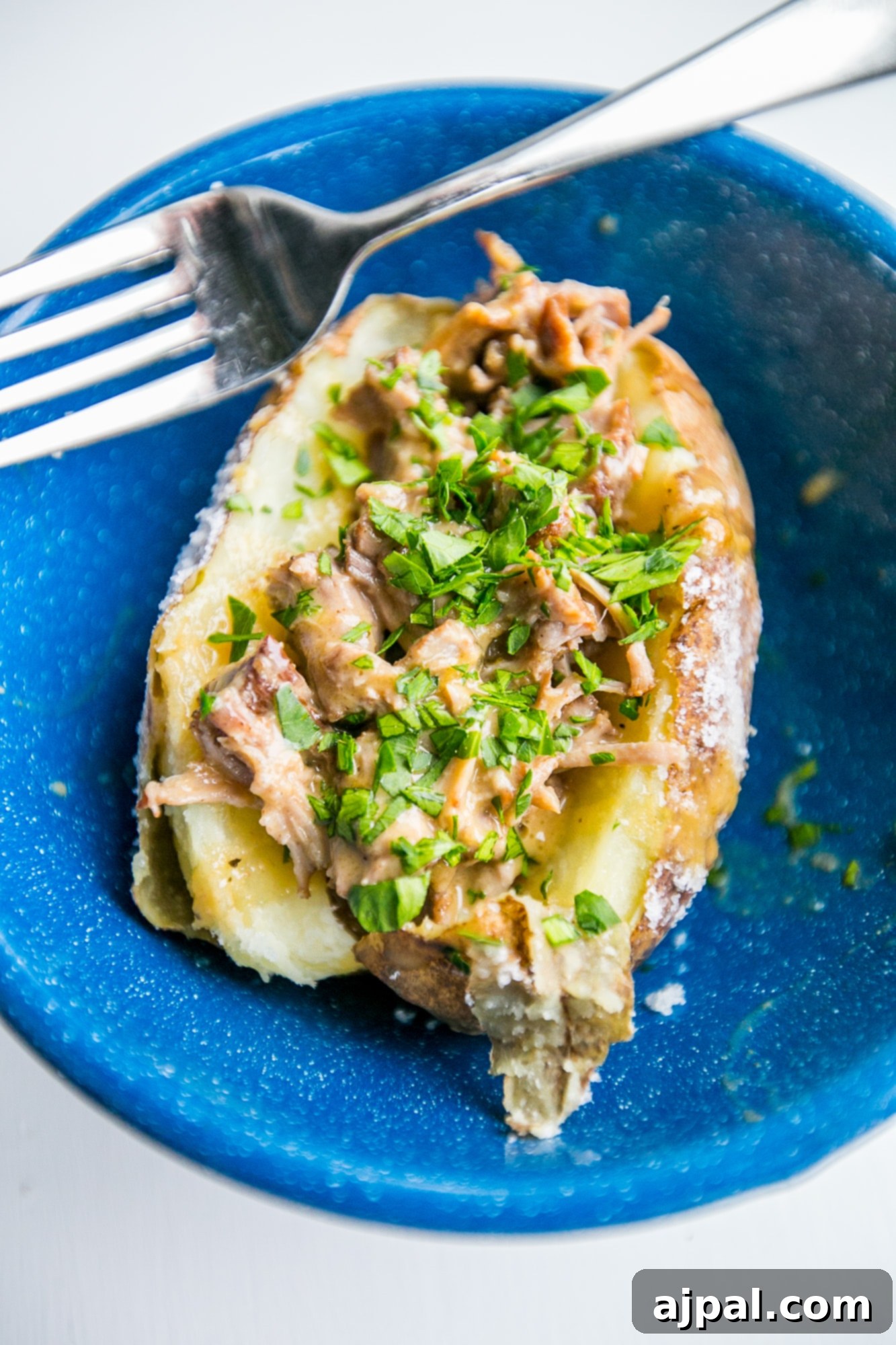 Delicious country rib stuffed potatoes with a white wine gravy, garnished with fresh herbs, ready to be served.