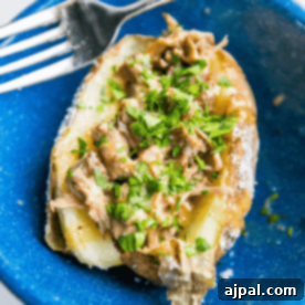 A blue plate with perfectly prepared country rib stuffed potatoes and fresh herbs.