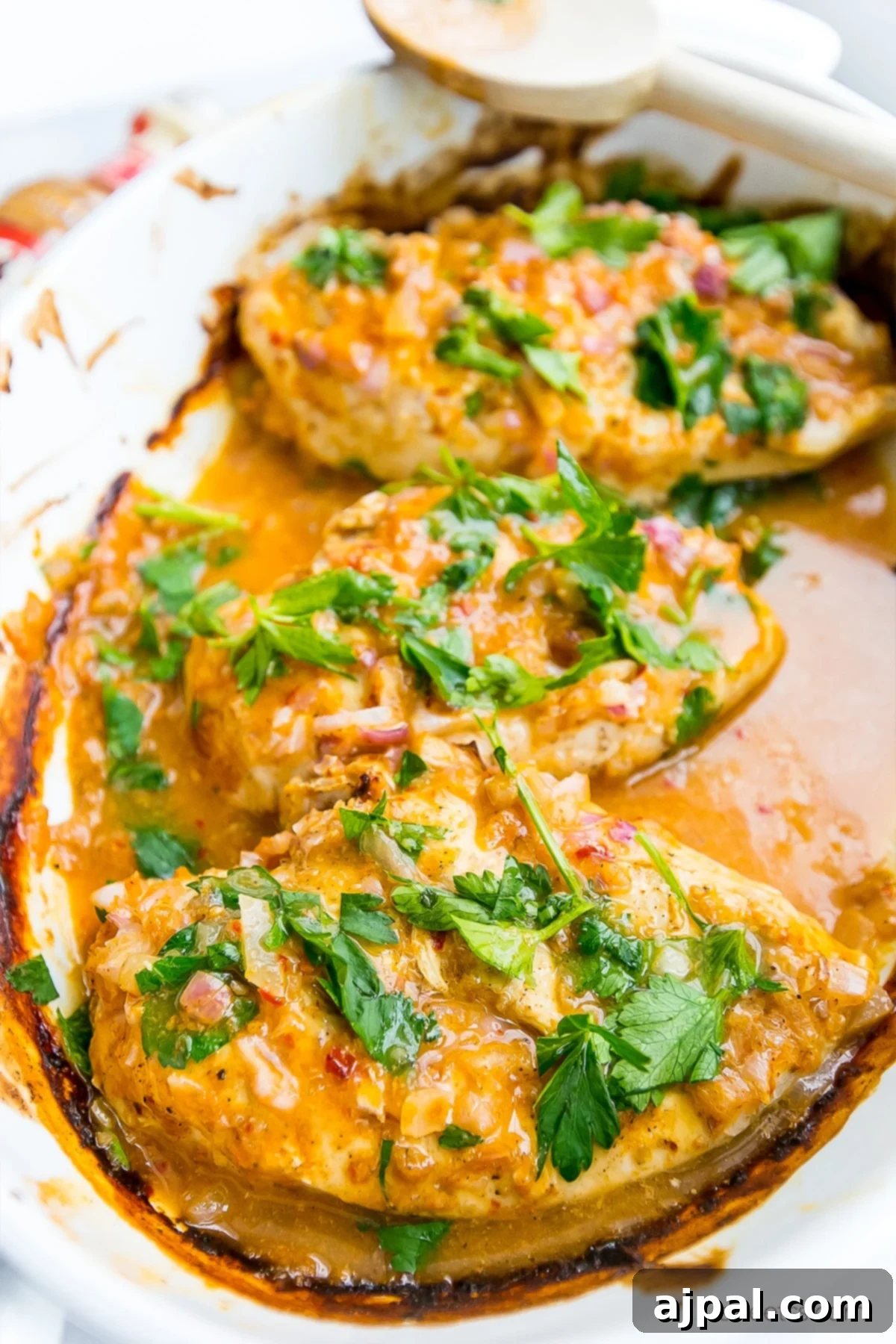 Easy 3 Ingredient Nandos Peri Peri Chicken 2 chicken in a pot with red sauce and fresh parsley on it