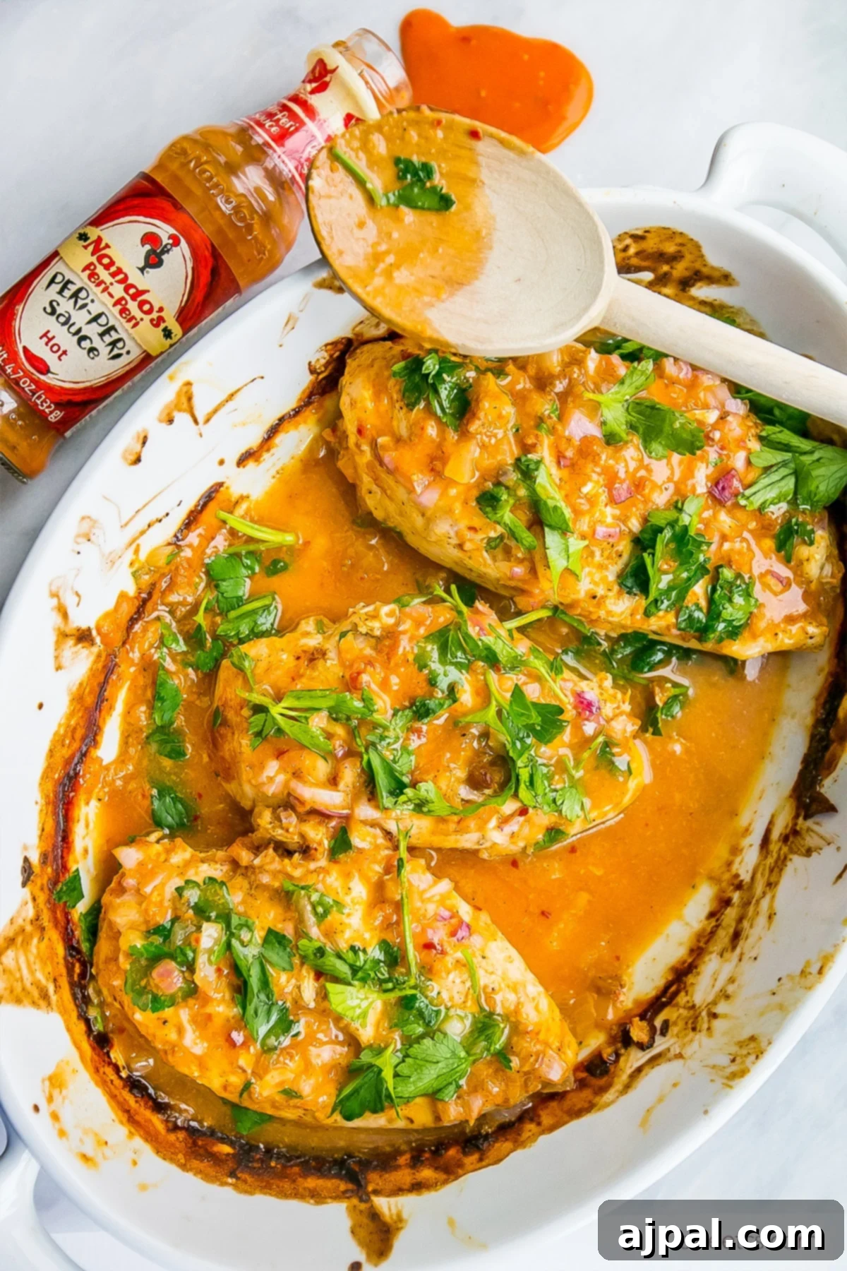 Easy 3 Ingredient Nandos Peri Peri Chicken 3 chicken in a pot with red sauce and fresh parsley on it